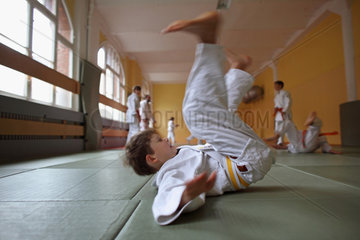 Berlin  Deutschland  Junge macht eine Rueckwaertsrolle in einem Judokurs
