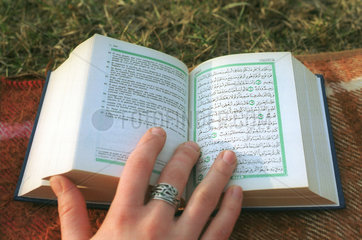 Haende blaettern im heiligen Koran.