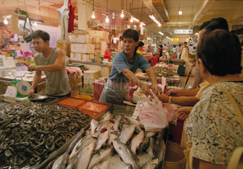 Fischhaendler bedient Kunden auf einem chinesischen Wochenmarkt