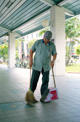 Aelterer Mann reinigt den Fussboden im Busbahnhof Tampines in Singapur