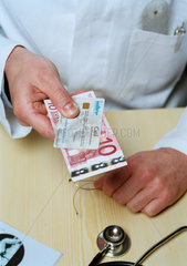 Arzt mit Privatversichertenkarte und Zehn Euro Schein