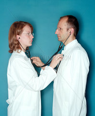 Aerztin und Arzt hoeren sich mit einem Stethoskop ab
