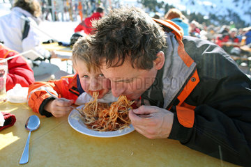 Jerzens  Oesterreich  Vater und Sohn essen Spaghetti von einem Teller