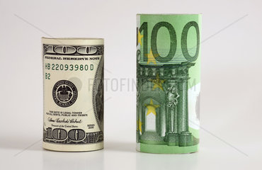 Gerollter 100-Dollarschein und 100-Euroschein stehen nebeneinander