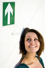 Berlin  Deutschland  lachende junge Frau vor Pfeil-Piktogramm