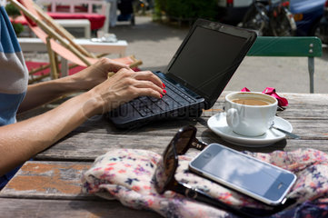 Berlin  Deutschland  eine Frau arbeitet in einem Strassencafe an ihrem Laptop