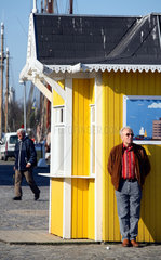 Eckernfoerde  Mann steht wartend an einer Verkaufsbude im Eckernfoerder Hafen