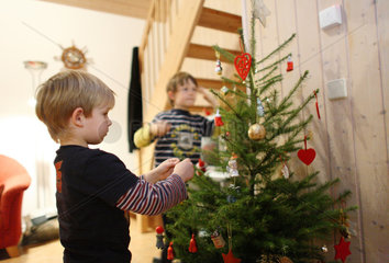 Wendisch Rietz  Deutschland  Junge schmueckt einen Weihnachtsbaum