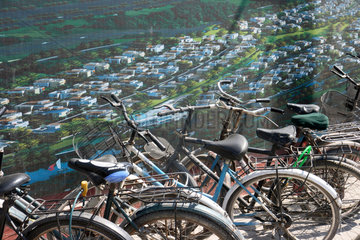 Peking  Fahrraeder stehen vor einem Bauplakat