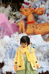 Ein Maedchen posiert vor einer kuenstlichen Weihnachtsdekoration in Hanoi