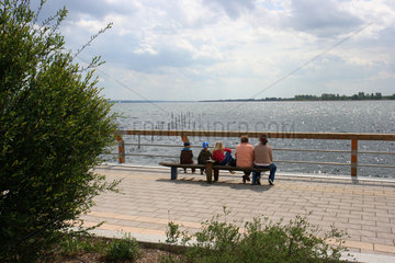 Prenzlau  Menschen sitzen an der Uferpromenade des Uckersees