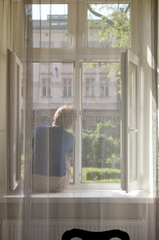 Krakau  Polen  Frau sitzt am Fenster mit Blick zum Klostergarten