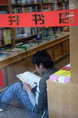 Peking  junger Chinese sitzt in einer Buchhandlung