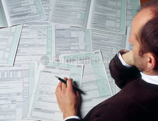 Ein Mann gruebelt ueber der Steuererklaerung 2003