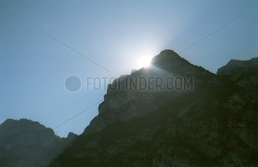 Die Sonne versinkt hinter einem Berg