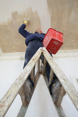 Mann beim Renovieren auf einer Leiter