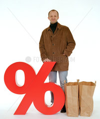 Ein Mann mit Tueten steht hinter einem Prozentzeichen