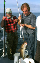 Angler auf der Ostsee mit einem Dorsch am Haken  Deutschland