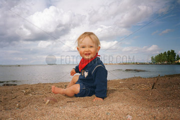 Kleinkind am Strand an einem See in Schweden