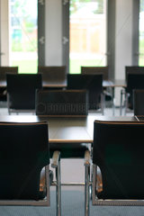 Konferenzsaal mit schwarzen Stuehlen und Tischen