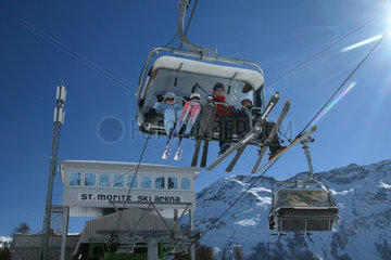 Skifahrer sitzen hoch oben in einer Seilbahn