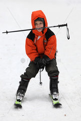 Berlin  Deutschland  Junge faehrt mit einem Skistock im Mund Ski