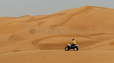 Ein Mann ist auf einem Quad in der Wueste unterwegs  Dubai
