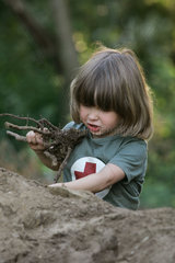 Ein Junge spielt im Sand mit einer Wurzel