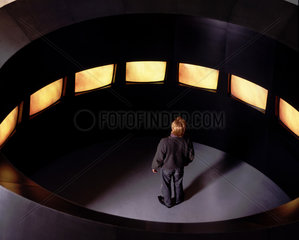 Ein Mann steht umgeben von Bildschirmen