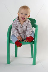 Ein glueckliches kleines Kind auf einem Stuhl