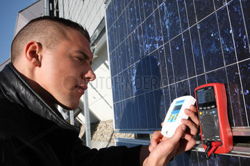 Berlin  Deutschland  Auszubildender misst Solarstrom eines Solar-Panels