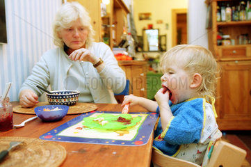 Ein Junge sitzt mit der Oma am Tisch und isst