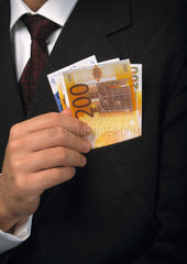 Mann im Anzug zieht Eurogeldscheine aus seiner Einstecktasche