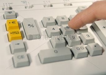 Ein Finger auf der Tastatur eines Rechengeraetes