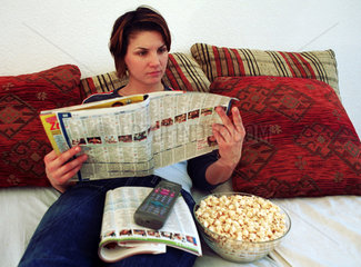 Eine junge Frau liest im TV-Programm