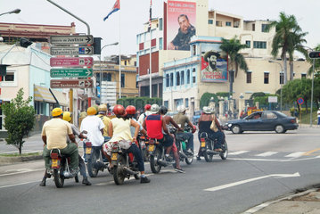 Santiago de Cuba  Kuba  Gruppe Motorradfahrer wartet an einer Keuzung  im Hintergrund die Parteizentrale der PCC