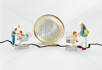 Miniaturfiguren vor einer stehenden Euromuenze