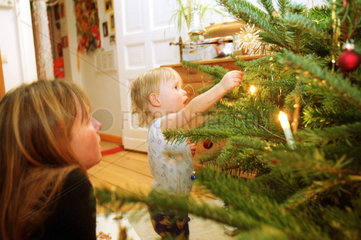 Mutter und Sohn schmuecken einen Weihnachtsbaum