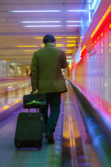 Ein Mann in einem Gang des Muenchener Flughafen auf einer Rolltreppe