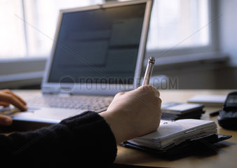 Nutzerin eines Notebooks an einem Schreibtisch  mit Kalender