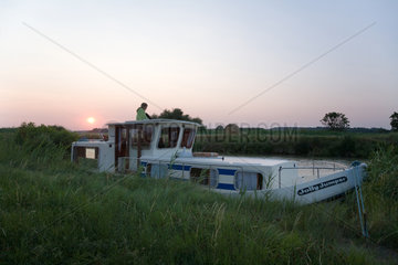 Agde  Frankreich  ein festgemachtes Hausboot bei Sonnenuntergang am Ufer