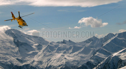 Ein Hubschrauber der Rettungswacht vor dem Panorama der Oestereichischen Alpen