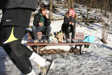 Berlin  Deutschland  ein junges Paar macht Picknick im Schnee  vorne ein Jogger