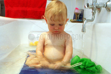 Ein Junge sitzt traurig in der Badewanne