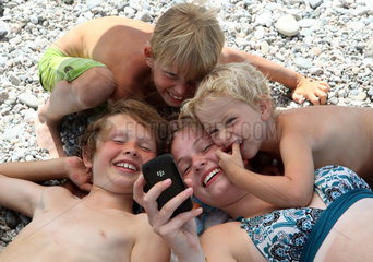 Fiumefreddo  Italien  lachende Kinder schauen auf ein Mobiltelefon