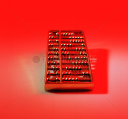 Ein Abakus aus Messing vor rotem Hintergrund