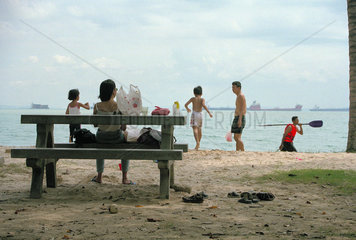 Familie beim Sonntagsausflug am Strand des East Coast Park in Singapur