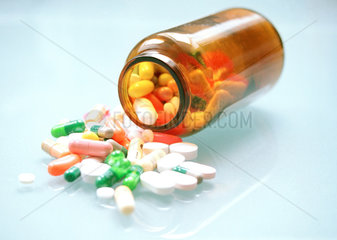 Liegende Tablettenflasche mit Medikamenten  die aus der Oeffnung herausgefallen sind