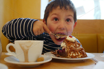 Ein Junge isst ein Stueck Torte