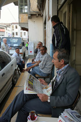 Nikosia  Tuerkische Republik Nordzypern  Mann liest Zeitung in einem Strassencafe